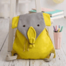 Crochetts - MOCHILA KOALA Sobre un suelo de madera blanca se encuentra la mochila Crochetts - MOCHILA KOALA, una mochila amarilla con una solapa gris con motivos de elefantes. Cerca, un taburete blanco sostiene libros y lápices, ideal para coger chupetes para bebés baratos o echar un vistazo a los productos para bebés con entrega gratis en Mallorca.