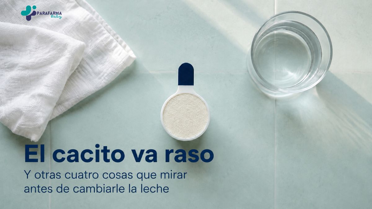 Cacito dosificador de leche infantil enrasado, junto a un vaso de agua sobre una encimera clara